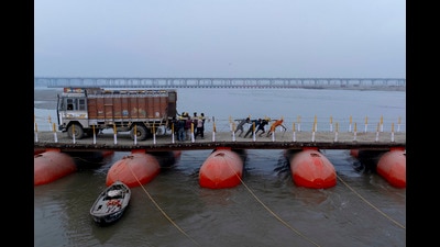 Labourers carry iron plates to construct a temporary road over pontoon bridge across the Ganga in Prayagraj on Sunday. (AP) Labourers carry iron plates to construct a temporary road over pontoon bridge across the Ganga in Prayagraj on Sunday. (AP)