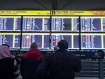 Passengers look at the information display board as many IndiGo flight services stand cancelled, at the Indira Gandhi International Airport, New Delhi
