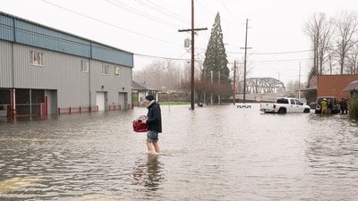 Brandon Phasith carries belongings while evacuating amidst rising floodwater, as an atmospheric river brings rain and flooding to the Pacific Northwest, in Sultan, Washington, U.S., December 10, 2025.  REUTERS/David Ryder (REUTERS)