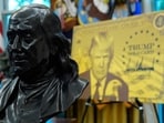 A bust of Benjamin Franklin, one of the founding fathers of the US, near a poster for the Trump Gold Card in the Oval Office of the White House