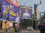 Commuters cross promotional posters and veiled statue of Lionel Messi, on the eve of his visit, in Kolkata Commuters cross promotional posters and veiled statue of Lionel Messi, on the eve of his visit, in Kolkata