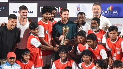 Lionel Messi presents a trophy to a football team. (PTI) Lionel Messi presents a trophy to a football team. (PTI)
