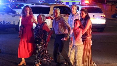 People cross a street next to police vehicles after a shooting incident at Bondi Beach in Sydney on December 14, 2025. (AFP) People cross a street next to police vehicles after a shooting incident at Bondi Beach in Sydney on December 14, 2025. (AFP)