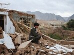 A boy sits next to his damaged house, in the aftermath of an earthquake, in Samangan province, Afghanistan, November 4, 2025. REUTERS/Sayed Hassib