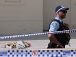 A police officer keeps watch near flowers laid in memory of the victims of a shooting at Bondi Beach in Sydney.