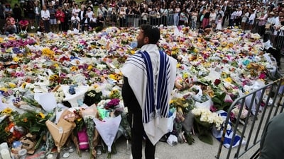 Rabbi Yossi Friedman speaks to people gathering at a flower memorial by the Bondi Pavilion at Bondi Beach on Tuesday (AP)