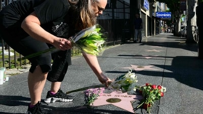 A woman places flowers at US actor and director Rob Reiner's Star on the Hollywood Walk of Fame in Los Angeles, California, on December 15, 2025 (Photo by Frederic J. Brown / AFP) (AFP) A woman places flowers at US actor and director Rob Reiner's Star on the Hollywood Walk of Fame in Los Angeles, California, on December 15, 2025 (Photo by Frederic J. Brown / AFP) (AFP)