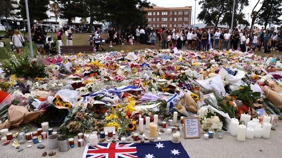 Mourners gather around floral tributes at Bondi Pavilion to honor the victims of the Bondi Beach shooting.