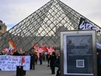 (FILES) A notice informs members of the public of the closure of the Louvre Museum as members of the French CGT union protest outside the entrance as museum workers voted to go on strike against increasingly deteriorating working conditions and the declining visitor experience at the world famous museum, in Paris on December 15, 2025. Hundreds of tourists lined up outside the Louvre Museum on December 17, 2025 as its opening was delayed while unions voted on continuing a strike over working conditions at the Paris landmark. The world's most visited museum had closed its doors to thousands of disappointed visitors on December 15 after workers went on strike and protested outside the entrance. (Photo by Blanca CRUZ / AFP)
