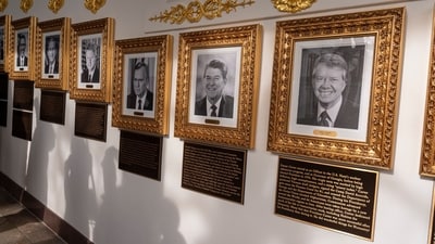 New plaques of explanatory text have been placed underneath presidential portraits on the Colonnade at the White House (AP) New plaques of explanatory text have been placed underneath presidential portraits on the Colonnade at the White House (AP)
