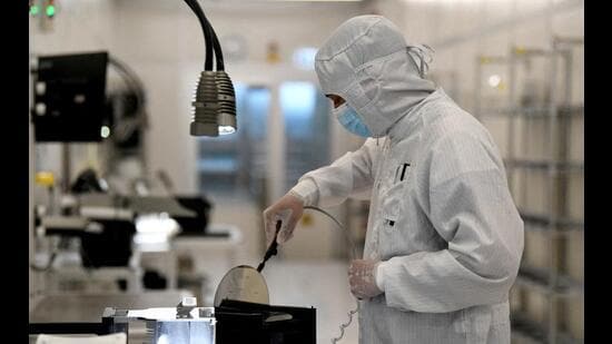 An employee works with a wafer on a production line of Dutch semiconductor company Nexperia in Hamburg, Germany. (REUTERS)