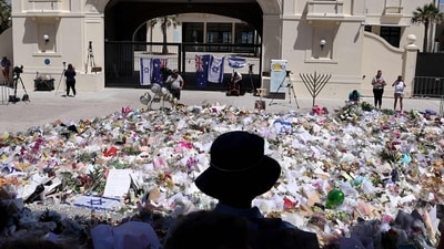 Mourners stand near tributes piled together at the front of the Bondi Pavilion. (AFP) Mourners stand near tributes piled together at the front of the Bondi Pavilion. (AFP)
