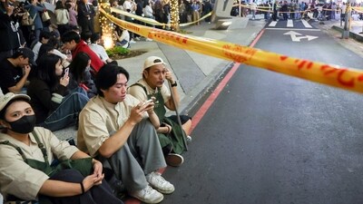 Staff from Eslite Spectrum Nanxi store near Zhongshan station wait to return to the building to collect their personal belongings while the building is cordoned off with yellow crime scene tape, following an incident in which several were injured after a person released smoke bombs and attacked bystanders, according to the government and local media, in Taipei, Taiwan, December 19, 2025. (REUTERS)