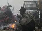 People warm themselves around a small fire on a foggy winter morning, in New Delhi, Saturday, Dec. 20, 2025. Visibility plunged across parts of Delhi on Saturday morning, with buildings and flyovers fading into a grey blur amid dense fog.