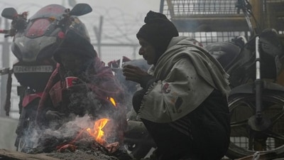 People warm themselves around a small fire on a foggy winter morning, in New Delhi, Saturday, Dec. 20, 2025. Visibility plunged across parts of Delhi on Saturday morning, with buildings and flyovers fading into a grey blur amid dense fog. (PTI)