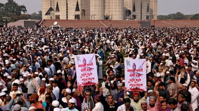 Men hold placards that read 'We all will be Hadi, we will keep fighting' as tens of thousands of people join the funeral prayer for Sharif Osman Hadi in Dhaka. (REUTERS)