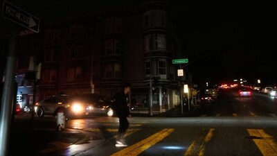 A pedestrian uses a flash light while crossing an intersection as power outages darken the streets, in San Francisco, Saturday, Dec. 20, 2025. (AP Photo/Jeff Chiu) (AP) A pedestrian uses a flash light while crossing an intersection as power outages darken the streets, in San Francisco, Saturday, Dec. 20, 2025. (AP Photo/Jeff Chiu) (AP)