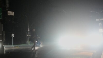A pedestrian crosses an intersection lit with headlights as power outages darken the streets, in San Francisco, Saturday, Dec. 20, 2025. (AP Photo/Jeff Chiu) (AP) A pedestrian crosses an intersection lit with headlights as power outages darken the streets, in San Francisco, Saturday, Dec. 20, 2025. (AP Photo/Jeff Chiu) (AP)
