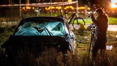 A forensics officer takes photographs of a car at the scene of a serious accident where a car drove through a crowd during a parade in Nunspeet. (AFP)