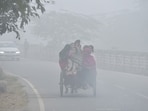 A family is seen traveling in a rickshaw on the Dasna service road near the Ghaziabad National Highway in the cold and fog ,in Ghaziabad , India on Monday,  December 22 2025.

