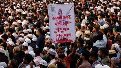 A man holds a placard that reads "We all will be Hadi, we will keep fighting" as tens of thousands of people join the funeral prayer for Sharif Osman Hadi, a student leader, who died after being shot in the head. (Reuters)