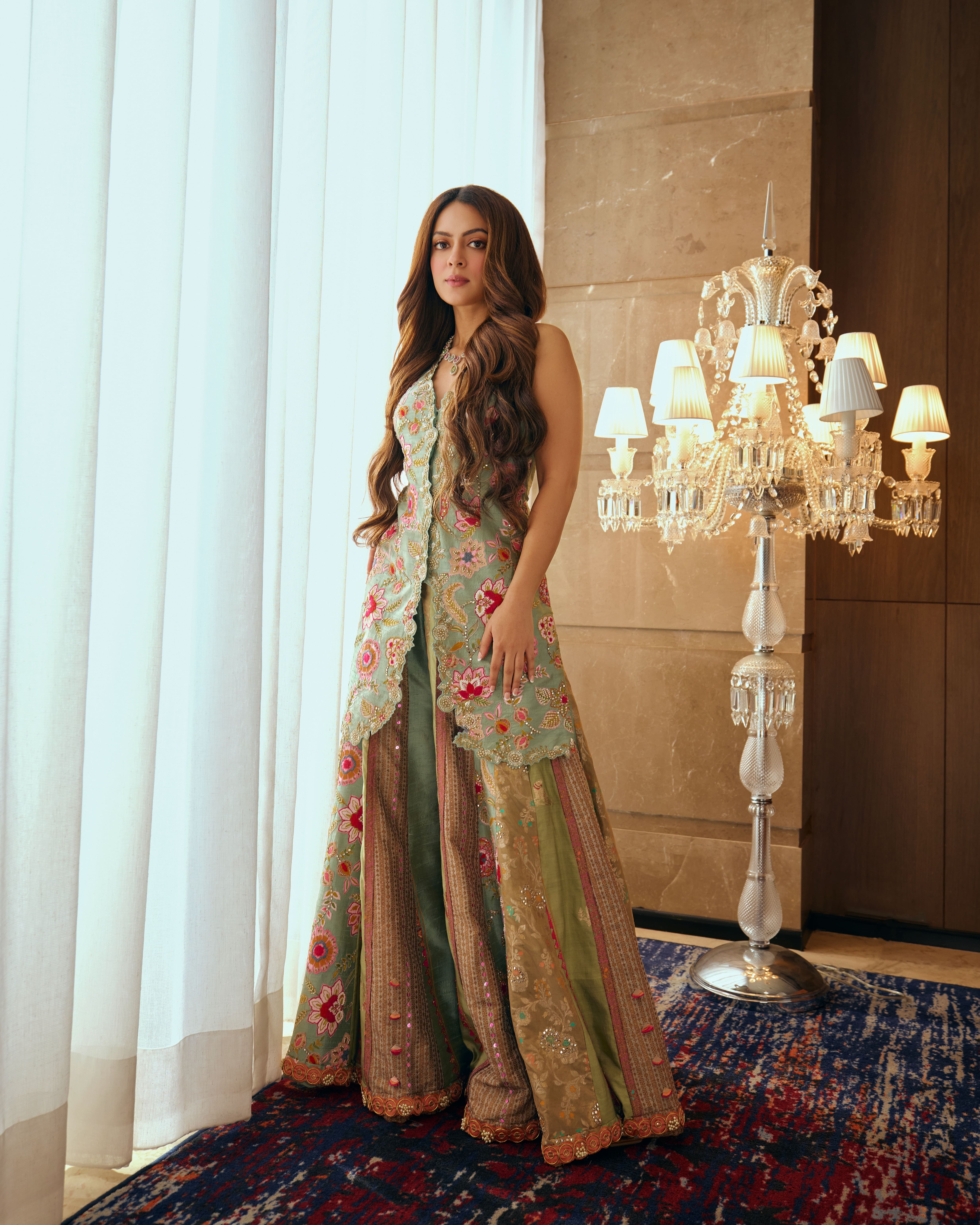 Outfit: Aum by Ashima and Asit. Jewellery: RK Jewellers. Anyaa stuns in a pastel green embroidered set from Aum by Ashima and Asit. The sleeveless long jacket is adorned with delicate pink, gold and cream florals, paired with fluid sharara pants. Finished with soft waves and beautiful jewels from RK Jewellers, the ensemble strikes the perfect balance between refined and effortless. Outfit: Aum by Ashima and Asit. Jewellery: RK Jewellers. Anyaa stuns in a pastel green embroidered set from Aum by Ashima and Asit. The sleeveless long jacket is adorned with delicate pink, gold and cream florals, paired with fluid sharara pants. Finished with soft waves and beautiful jewels from RK Jewellers, the ensemble strikes the perfect balance between refined and effortless.