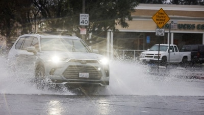 Cars drive through puddles as heavy rain falls due to an atmospheric river, in an intersection in the Woodland Hills area of Los Angeles (REUTERS)