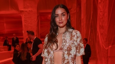 Ana de Armas at the Louis Vuitton Spring-Summer show in an embroidered rusted bronze gold outfit featuring a half-sleeved open shirt, silk-satin bralette, and high-waisted straight-fit pants. She styled the ensemble with high heels, an LV handbag, rings, a dainty bracelet, a matching chain, earrings, open tresses, and striking glam picks. (Vianney Le Caer/Invision/AP) Ana de Armas at the Louis Vuitton Spring-Summer show in an embroidered rusted bronze gold outfit featuring a half-sleeved open shirt, silk-satin bralette, and high-waisted straight-fit pants. She styled the ensemble with high heels, an LV handbag, rings, a dainty bracelet, a matching chain, earrings, open tresses, and striking glam picks. (Vianney Le Caer/Invision/AP)