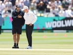A match official and a curator look at the playing surface at the MCG.