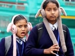 Girls clad in warm clothes on their way to school on a cold winter morning, in Lucknow on Tuesday.
