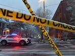 A police vehicle is parked at an intersection near crime scene tape. A police vehicle is parked at an intersection near crime scene tape.