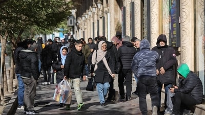 People walk past stores as the value of the Iranian Rial drops, in Tehran, Iran, on December 30, 2025. (via REUTERS)