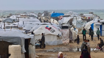 Displaces palestinians walk near tents and makeshift shelters as the region experiences cold winter conditions in Al-Mawasi refuge camp in the southern Gaza Strip on December 29, 2025. (AFP) Displaces palestinians walk near tents and makeshift shelters as the region experiences cold winter conditions in Al-Mawasi refuge camp in the southern Gaza Strip on December 29, 2025. (AFP)