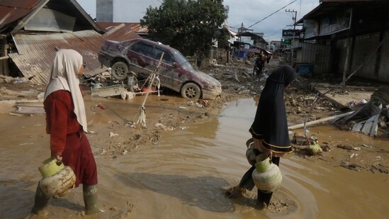 Survivors walk past the wreckage of a car at an area affected by flash flooding in the aftermath of Cyclone Senyar in Aceh Tamiang, on Sumatra Island, Indonesia, Thursday, Dec. 4, 2025.&nbsp;(AP)