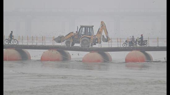 Commuters cross a pontoon bridge on a chilly and foggy day in Prayagraj on Tuesday (HT Photo)