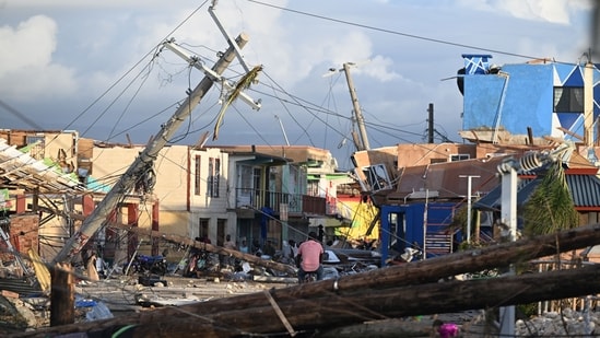 Electrical poles are down as a man bikes through the destroyed neighborood of North Street following the passage of Hurricane Melissa, in Black River, Jamaica on October 29, 2025.(AFP)
