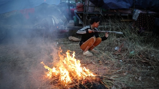 A woman burns grass to keep warm in a refugee camp after evacuation, amid deadly clashes between Thailand and Cambodia along a disputed border area, in Srei Snam, Siem Reap Province, Cambodia, December 10, 2025.(REUTERS)