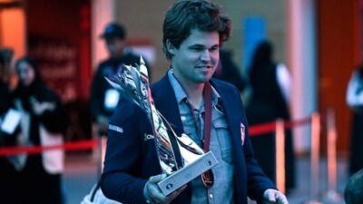 Norway's Magnus Carlsen walks with the winner's trophy after the FIDE World Rapid and Blitz Championship in Doha (AFP) Norway's Magnus Carlsen walks with the winner's trophy after the FIDE World Rapid and Blitz Championship in Doha (AFP)
