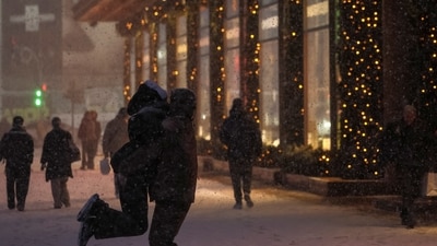 A serviceman hugs a girl as they dance under the snowfall near New Year displays at a shopping mall, amid Russia's attack on Ukraine, in Kyiv, Ukraine. (REUTERS)