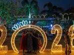 Revellers pose for photographs at an illuminated sea promenade during New Year's Eve in Mumbai.