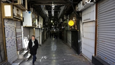 People walk past closed shops following protests over a plunge in the currency's value, in the Tehran Grand Bazaar, Tehran, Dec. 30. People walk past closed shops following protests over a plunge in the currency's value, in the Tehran Grand Bazaar, Tehran, Dec. 30.
