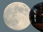 The moon rises on the eve of a Wolf Moon supermoon as passengers look out from a pod on the London Eye wheel in London.