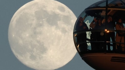 The moon rises on the eve of a Wolf Moon supermoon as passengers look out from a pod on the London Eye wheel in London. (Reuters)