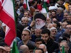 A demonstrator holds up a poster of the Iranian Supreme Leader Ayatollah Ali Khamenei next to the Iranian flags A demonstrator holds up a poster of the Iranian Supreme Leader Ayatollah Ali Khamenei next to the Iranian flags