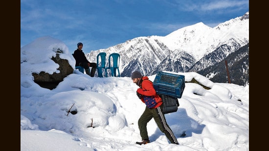 A man carrying crates on a snow-covered hill in Sonamarg on Tuesday. (REUTERS)