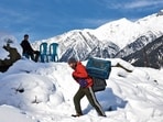 A man carrying crates on a snow-covered hill in Sonamarg on Tuesday. (REUTERS)