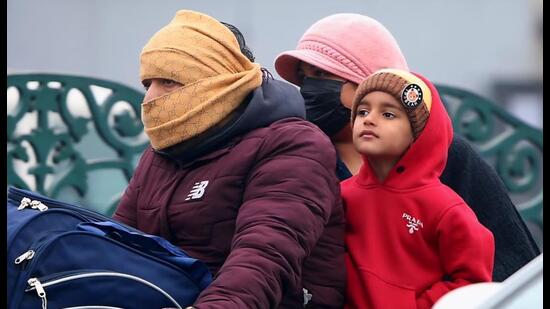 A family braving the winter chill at a traffic crossing in Bathinda on Wednesday. Residents were wrapped up in woollens to brave the biting cold. (Sanjeev Kumar/HT)