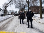 Minneapolis Police officers look on as members of law enforcement hold a perimeter around the scene where Renne Nicole Good was shot.