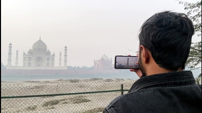 A man clicks a picture of the Taj Mahal at the Taj Viewpoint as a thick layer of fog engulfs the monument amid intensifying cold, in Agra on Sunday. (ANI Video Grab) A man clicks a picture of the Taj Mahal at the Taj Viewpoint as a thick layer of fog engulfs the monument amid intensifying cold, in Agra on Sunday. (ANI Video Grab)