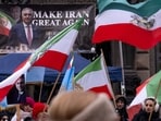 Protesters hold up placards featuring Reza Pahlavi, the son of the last shah of Iran, as they wave Pahlavi-era Iranian flags during a demonstration against the Iranian government at Stephansplatz square in Vienna, Austria, on January 11, 2026.